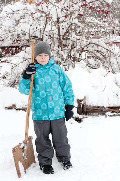 En pojke med en trä spade för snöröjning — Stockfoto