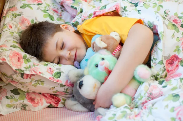 O menino dorme com brinquedos suaves — Fotografia de Stock