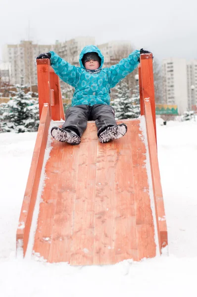 Pojken är ridning en trä kullar på vintern — Stockfoto