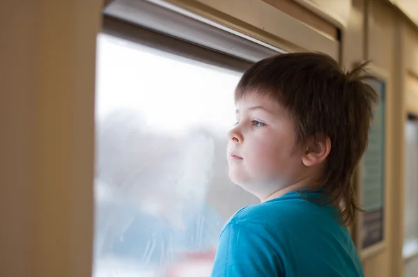 A boy looks out the window the train — Stock Photo, Image