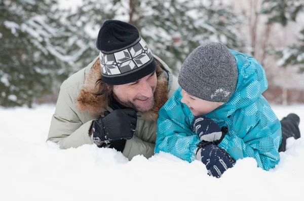 Papa et fils se reposent dans la neige dans le parc — Photo