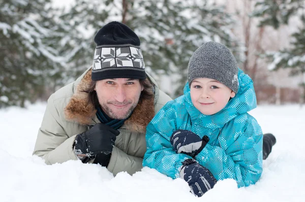 Vader en zoon rusten in de sneeuw in het park — Stockfoto