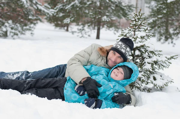 Papa et fils se reposent dans la neige dans le parc — Photo