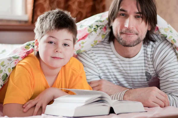 Pappa och son läsning i sängen — Stockfoto