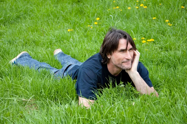 Mężczyzna w średnim wieku jest w stanie spoczynku na trawie — Zdjęcie stockowe