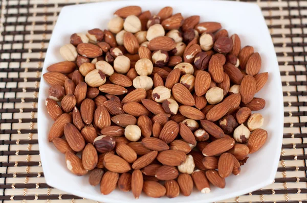 Roasted almonds and hazelnuts on a plate — Stock Photo, Image