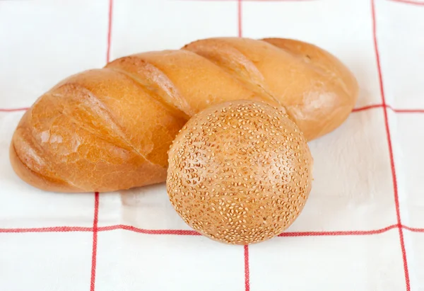 Sliced bread and bun with sesame seeds — Stock Photo, Image