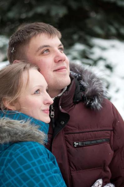 Unga älskande kvinna och man i en vinter skog — Stockfoto