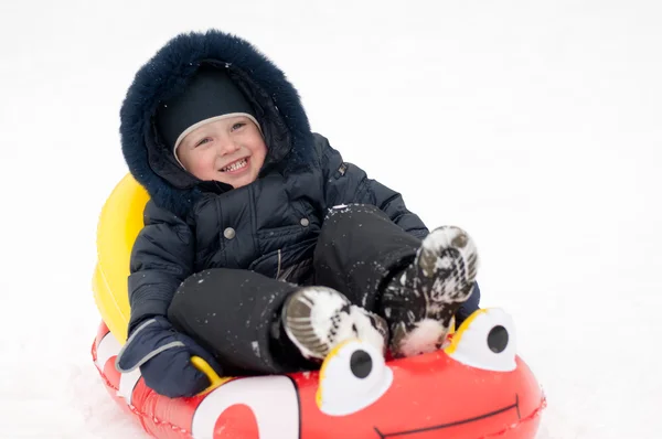 Das Kind reitet im Winter die Hügel hinunter — Stockfoto