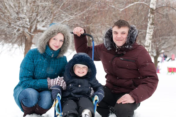 Familjen promenader i parken under vintern snöfall — Stockfoto