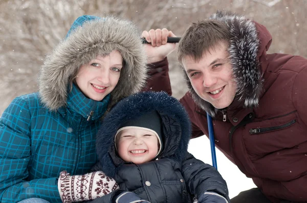 Familjen promenader i parken under vintern snöfall — Stockfoto