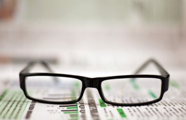 Eyeglasses lying around newspapers clipart