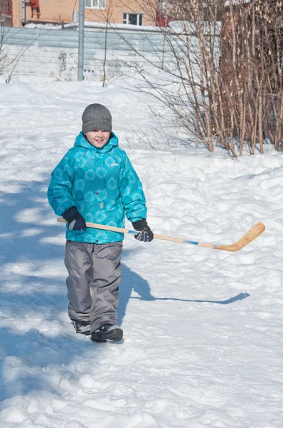 一个男孩玩曲棍球在雪中 — 图库照片