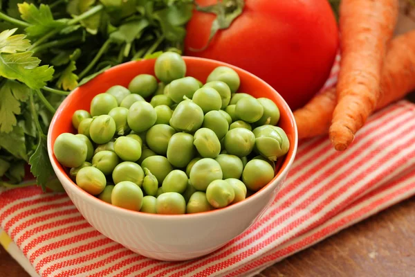 Closeup on bowl of fresh green organic green peas and vegetables — Stock Photo, Image