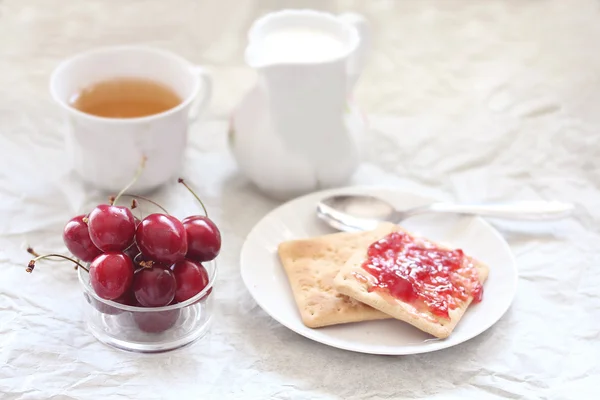Café da manhã com cereja e geléia em torradas, chá, leite — Fotografia de Stock