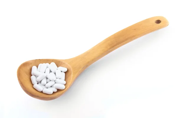 Wooden spoon with pills — Stock Photo, Image