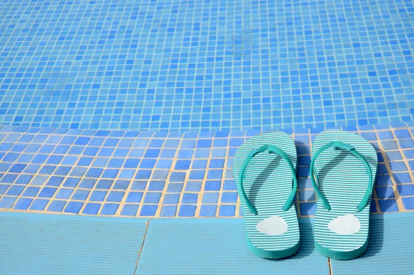 Chinelos femininos perto da piscina tropical — Fotografia de Stock