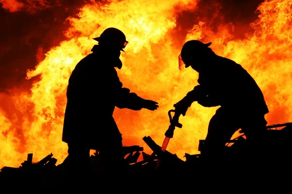 Zwei Feuerwehrleute und riesige Flammen Stockbild