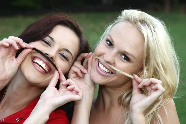 Amigos divirtiéndose con bigotes simulados — Foto de Stock