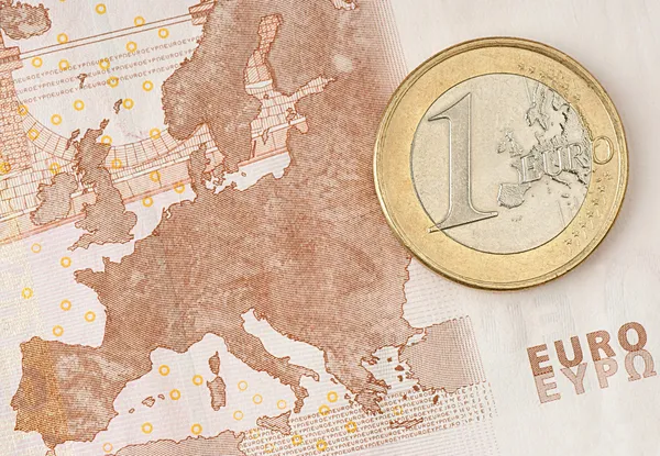 Ένα ευρώ νόμισμα σε ορισμένου τραπεζογραμματίου ευρώ, παρουσιάζοντας χάρτη της Ευρώπης Φωτογραφία Αρχείου