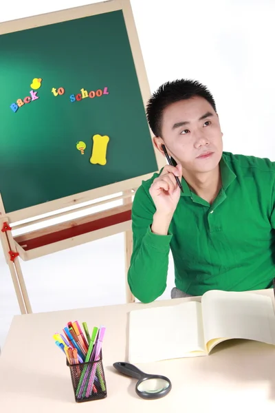 Student setting by a desk in the front of the blackboard. — Stock Photo, Image