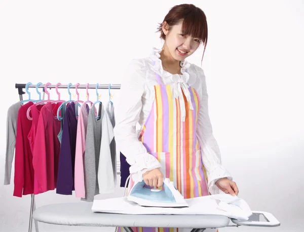 Una mujer china está usando una plancha eléctrica con mucha ropa . — Foto de Stock