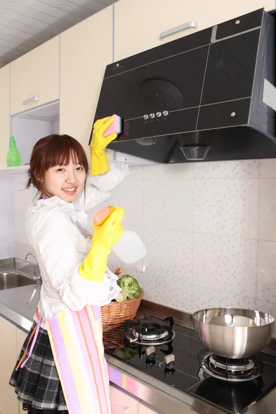 En kinesisk kvinna rengöring i kök. Stockfoto