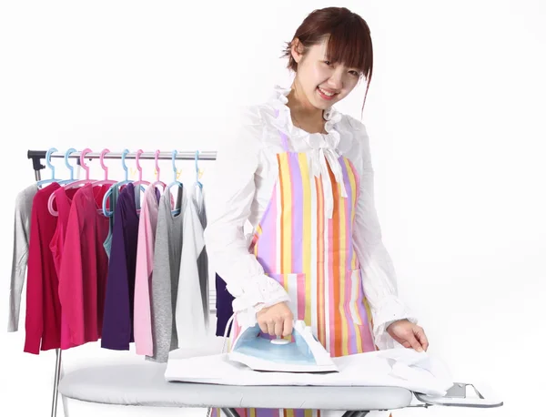 Eine Chinesin benutzt ein elektrisches Bügeleisen mit vielen Kleidungsstücken. — Stockfoto