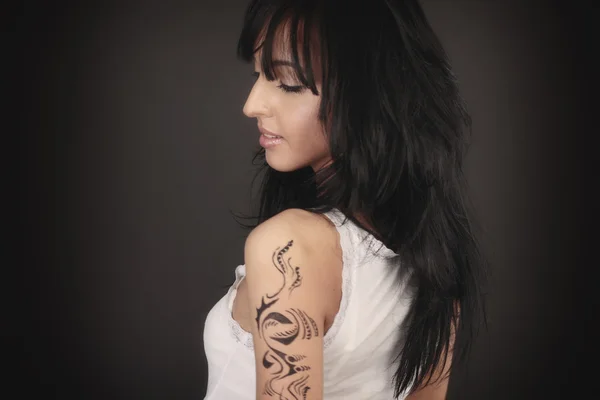 Model in witte kleren met tatoeage op haar arm — Stockfoto