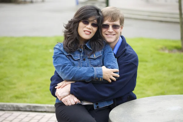 Bonito caucasiano, casal asiático sentado ao ar livre juntos, abraço — Fotografia de Stock