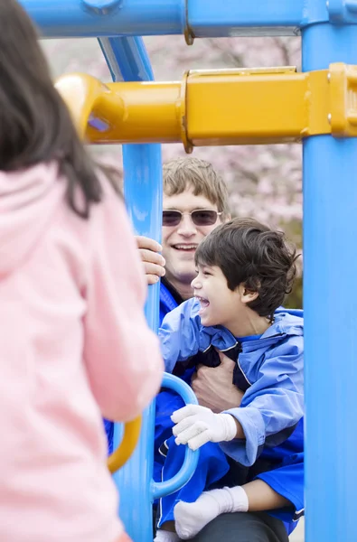 Отец играет на детской площадке с сыном-инвалидом — стоковое фото