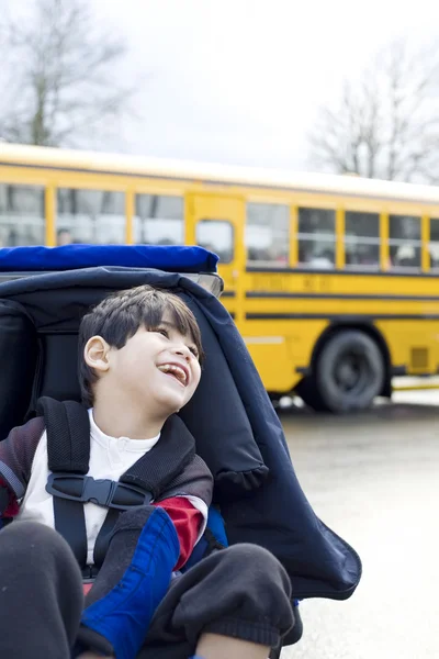 Deficiente menino de cinco anos em cadeira de rodas, de ônibus escolar — Fotografia de Stock