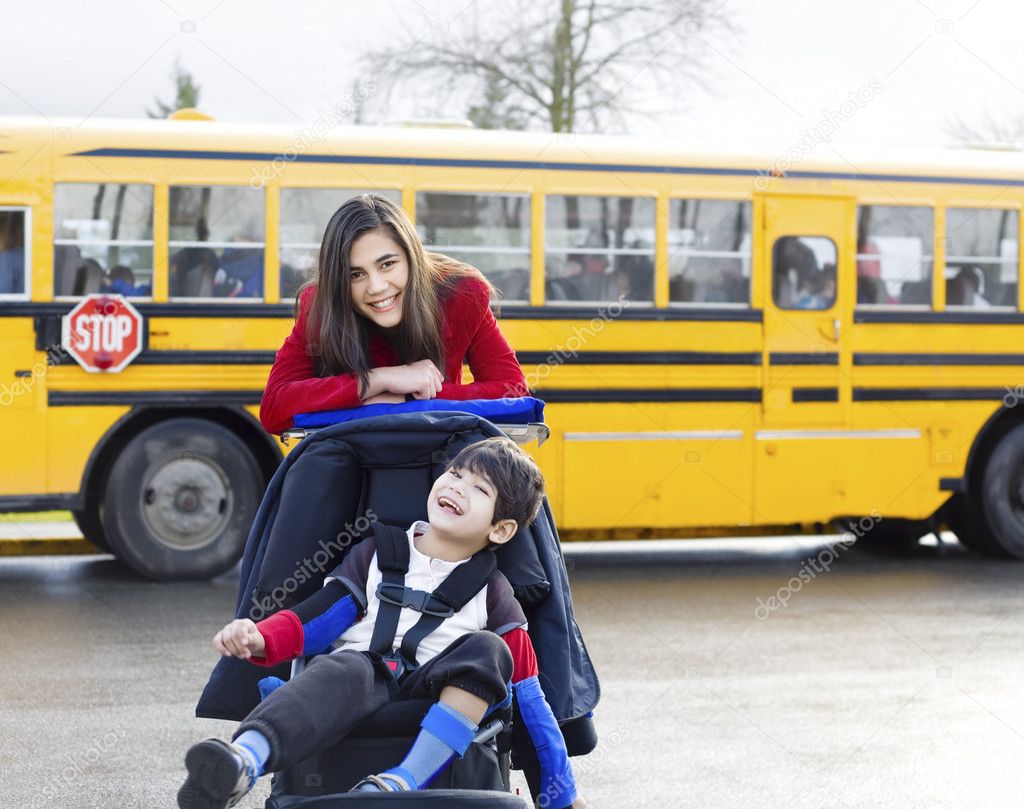Big sister with disabled brother in wheelchair by school bus