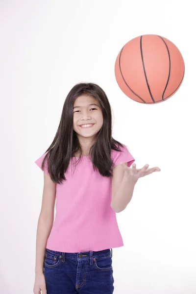 Niña asiática de diez años sosteniendo baloncesto, aislada en blanco — Foto de Stock
