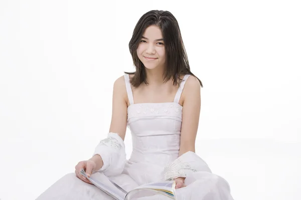 Beautiful young teen girl in white dress sitting reading a magaz — 图库照片