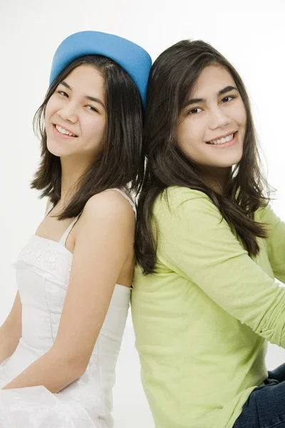 Twee jonge tiener meisjes rug aan rug vergadering samen, geïsoleerd op — Stockfoto
