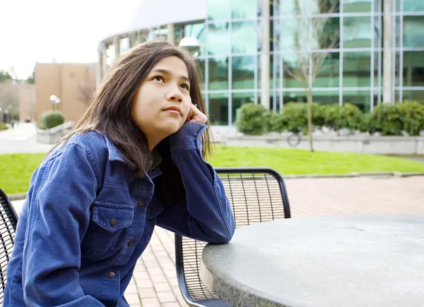 Девочка-подросток, сидящая на улице, глядя в небо — стоковое фото