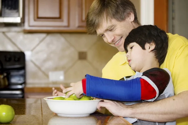 Ojciec pomoc niepełnosprawny syn z pracy w kuchni — Zdjęcie stockowe