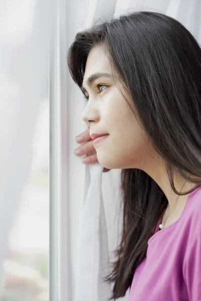 Side profile of teen girl looking out window — Stockfoto