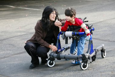 Mother with disabled son in walker clipart