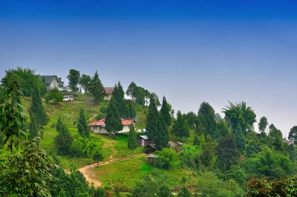 El valle verde, camino de pueblo y cabañas con cielo azul Imagen de stock