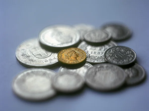 Monedas suizas sobre fondo azul . — Foto de Stock