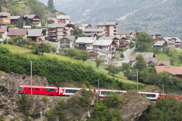 Ledovec expresní vlak projede kolem vesnice, Švýcarsko — Stock fotografie