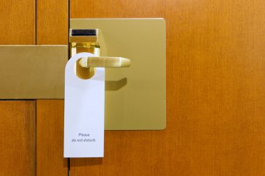 Do not disturb sign on brass and wood hotel room door clipart