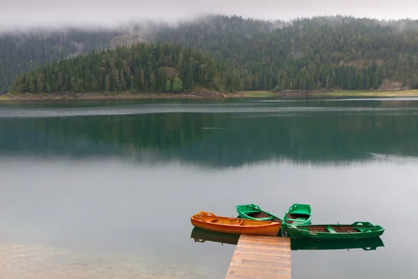 Lac de montagne arrosé noir avec jetée de bateau — Photo