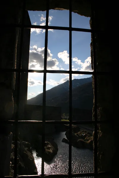 Vergitterte Burgfenster mit Blick auf glitzernden Teich — Stockfoto