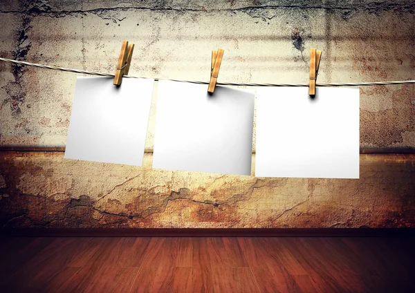 Білі папери прикріплені до мотузки з шпильками для одягу на гранжевому фоні стіни — стокове фото