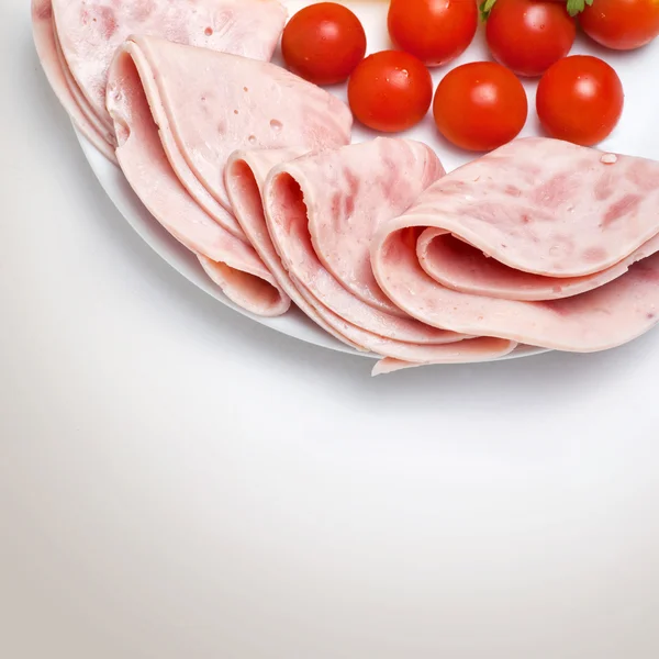 Plasterki szynki na płytce z pomidorami — Zdjęcie stockowe