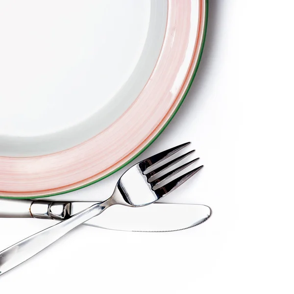 Coltello, piatto bianco e forchetta su sfondo bianco — Foto Stock