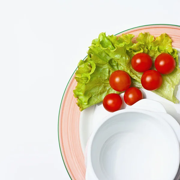 Empty white bowl on a plate with tomatoes and salad — Stock Photo, Image